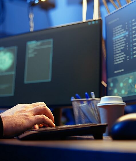 Hackers typing fast on keyboard in graffiti painted hideout, rushing to finish developing spyware software, using it to gather data from users computers without their knowledge, camera A close up