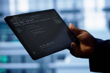 Programmer monitoring server room rigs, doing checkup, inputting data on tablet of needed fixes. IT specialist working in data center facility housing storage hardware, camera A close up