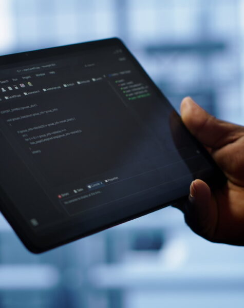 Programmer monitoring server room rigs, doing checkup, inputting data on tablet of needed fixes. IT specialist working in data center facility housing storage hardware, camera A close up